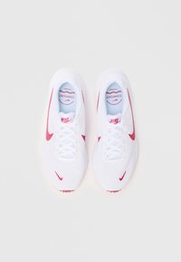 Witte mesh sneakers met roze accenten, ronde neus, vetersluiting en gevoerde binnenzool. Heeft het label 'Comfort' op een lichtblauwe achtergrond.