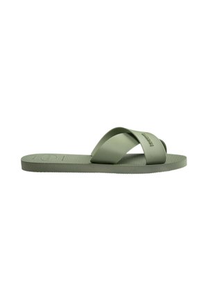 Sandalia plana verde oliva con suela texturizada y dos tiras anchas superpuestas que cruzan sobre el pie.