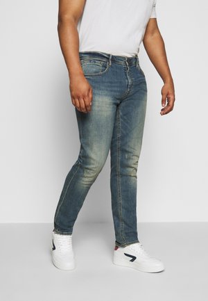 Jeans de corte skinny en un lavado azul deslavado, con diseño de cinco bolsillos y sutiles desgastes. Combinados con zapatillas blancas.