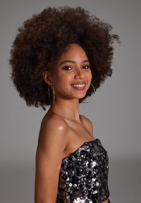 Top sans bretelles noir en sequins avec un design ajusté. Présente des sequins circulaires qui reflètent la lumière. Texture lisse et décolleté ouvert.