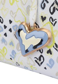 White bag with colorful heart patterns, featuring a gold heart-shaped charm with blue, black, and cream accents. Textured surface.