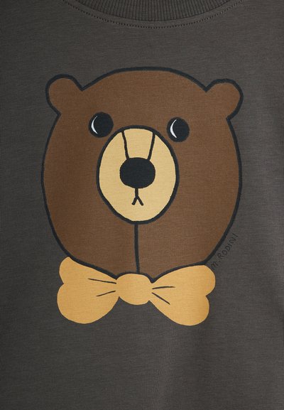 Ein Grafik von einem Braunbären mit einer gelben Fliege auf einem dunkelgrauen Stoffhintergrund. Der Bär hat große schwarze Augen und ein einfaches, cartoonhaftes Design.