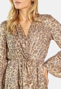 Leopardenmuster-Kleid in metallischem Gold und Braun, mit tiefem V-Ausschnitt, langen Ärmeln, gebundenem Taillenbund und weichem, strukturiertem Stoff.