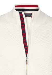Maglione zip-up bianco con texture, colletto a righe rosse, blu navy e bianche e testo "FELIX HARDY" sulla pattina del zip interna.