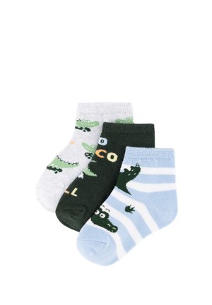 Tres pares de calcetines para niños pequeños con diseños de cocodrilos: blancos con cocodrilos verdes, verde oscuro con texto y azules con rayas blancas y cocodrilos.