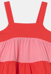 Czerwona i różowa sukienka bez rękawów z szerokimi ramiączkami, z warstwowym fasonem i marszczonym materiałem oraz kontrastowymi blokami kolorystycznymi. Miękka bawełniana tekstura.