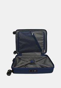 Valigia rigida della marina con quattro ruote, aperta che mostra l'interno grigio, tasca in rete, cinghie per fissare gli oggetti e una combinazione di lucchetto integrata.