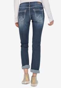 Jeans dżinsowe w ciemnym odcieniu z wyblakłym efektem, z podwiniętymi nogawkami. Posiadają dwie tylne kieszenie z haftowanymi detalami.