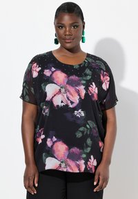 Top nero con stampa floreale in rosa e verde, maniche corte, scollo rotondo e decorazioni. Tessuto morbido con un design fluido.