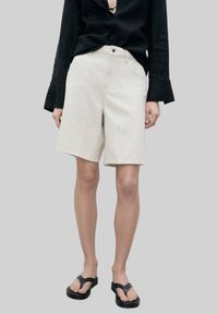 Wit gestreepte shorts met een ontspannen pasvorm, voorzien van een tailleband en zakken, gecombineerd met een zwart longsleeve shirt en zwarte slippers.