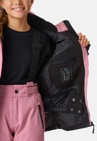 Veste de ski rose avec doublure noire, sangles réglables, poche intérieure et étiquette de marque. Tissu lisse et durable avec un design élégant.