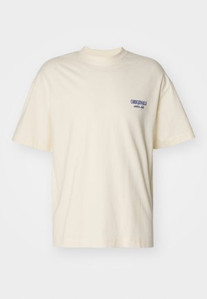 T-shirt a maniche corte di colore crema in cotone. Presenta un piccolo logo blu "ORIGINALS" sul lato sinistro del petto. Design classico con colletto a girocollo.