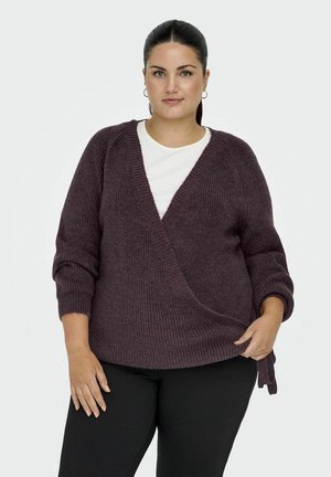 Burgundský kardigan ve stylu zavinovacího designu s texturovaným pletením, hlubokým výstřihem do V a plnými rukávy, v kombinaci s bílou košilí pod ním a černými kalhotami.