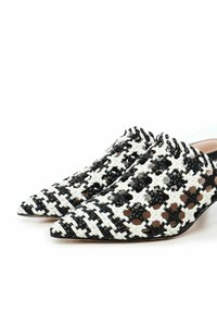Woven black and white pointed-toe shoes with a cut-out design. Smooth inner lining and a slight heel. Unique texture and pattern visible.