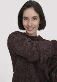 Flauschiger Strickpulli in dunklem Burgunderrot. Mit weiten Ärmeln und einem strukturierten Muster. Weiches, warmes Material mit einem gerippten Halsausschnitt.