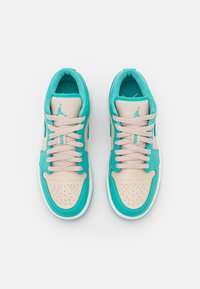 Baskets basses turquoise et beige avec bouts perforés, panneaux en cuir contrastants et lacets plats. Logo visible sur la languette.