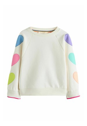Sweat-shirt crème à manches longues avec des patchs colorés en forme de cœur sur les deux manches et une bordure rose aux poignets.
