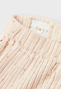 Tejido de punto de color rosa claro con puntos en relieve, con una cinturilla elástica y una etiqueta interior blanca con un cierre de botón.