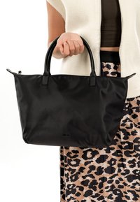 Zwarte nylon draagtas met twee handvatten, een gladde textuur en een ritssluiting. Geaccentueerd met zwarte leren details.