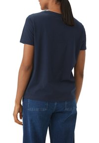 Navyblaues Baumwoll-T-Shirt mit Rundhalsausschnitt und kurzen Ärmeln, das minimalistische Nähdetails und einen lässigen Schnitt aufweist.