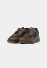 Brown mesh and synthetic sneakers with a round toe, featuring lace closure and a textured rubber sole. Branding appears on the tongue.