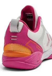 Hvid atletiksko med lyserøde accenter, tekstureret overdel, mesh-panel og orange detalje på hælen. Har en træksnor og tydeligt brandlogo.