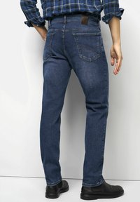 Donkerblauwe denim jeans met een rechte snit, vijf zakken en een bruine leren patch bij de tailleband. Soepele textuur, stevige constructie.