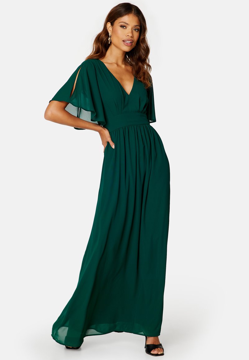 Robe longue verte avec un décolleté en V profond, des manches en cape, une taille froncée et une jupe fluide. Fabriquée en tissu léger.