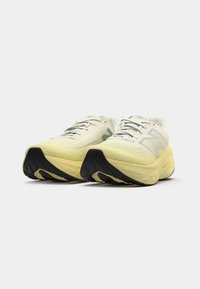 New Balance tenisice s bijelim i svijetlo žutim dizajnom, teksturiranim gornjim dijelom, zelenim akcentima i crnim gumiranim potplatom.