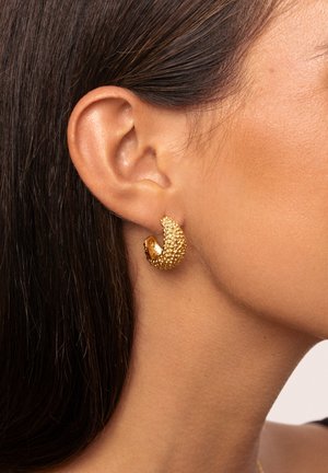 Orecchini a cerchio in oro con una superficie texturizzata e luccicante e un design elegante e curvo. Mettono in risalto una sezione interna lucidato.