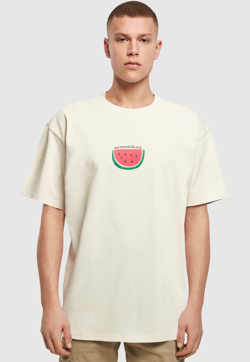 Beige bomull t-skjorte med korte ermer og en avslappet passform. Har en rund vannmelon grafikk med teksten "sommer" i et lekent skrifttype.