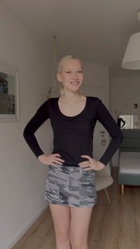 Čierne tričko s dlhým rukávom a výstrihom do lodi, skombinované so sivou mini sukňou s maskáčovým vzorom, vreckami vpredu a pásikom.