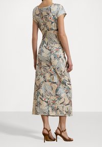 Maxi šaty s květinovým potiskem z měkké tkaniny, s kulatým výstřihem a krátkými rukávy. Barevná paleta zahrnuje béžovou, modrou, oranžovou a zelenou.