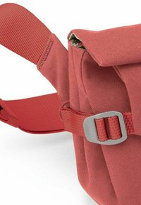 Bolso de hombro de tela roja con superficie texturizada, correa ajustable y detalle de hebilla gris. El cierre de solapa revela el interior del bolso.