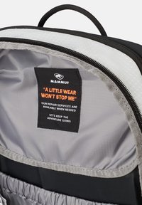 Zwart en grijze rugzakinterieur met een gladde textuur en een ritszak. Bevat een stoffen label met oranje tekst en logo.