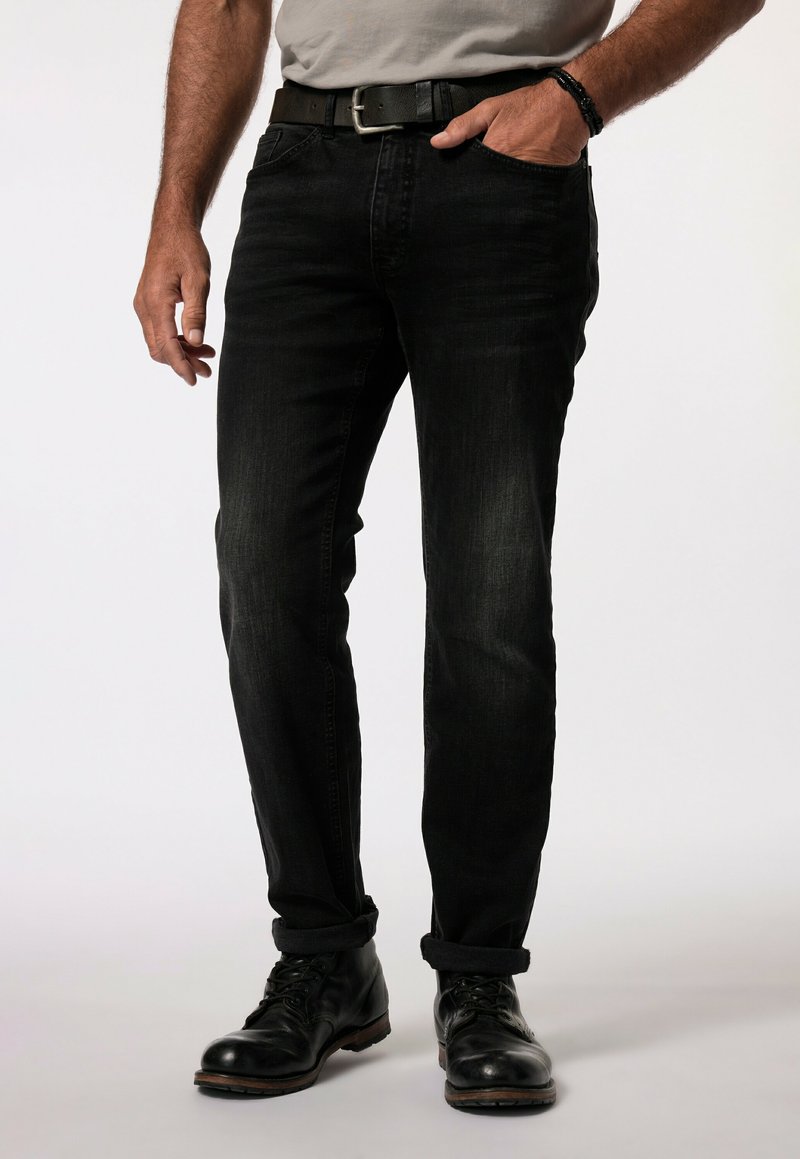 Jeans in denim nero con vestibilità dritta, tasche anteriori visibili e orli risvoltati, abbinati a stivali in pelle nera e una camicia grigia.