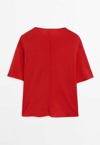 Chemise rouge à manches courtes avec une coupe large et un détail de couture centrale dans le dos, présentée à plat sur fond blanc.