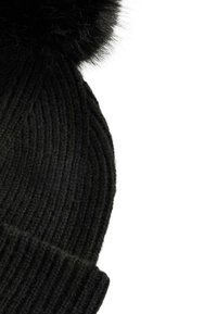 Czarna dzianinowa czapka z pionowym prążkowanym splotem i dużym czarnym futrzanym pomponem na górze. Tkanina wydaje się miękka i gruba.