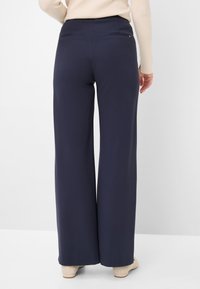 Navy wide-leg trousers made from a smooth fabric, featuring a fitted waistband, back pockets, and a slight sheen finish.