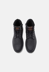 Mustat nahka-apinat kengät, joissa on turkiksella vuorattu sisus, nauhakiinnitys, sivuvetoketjut ja kumipohjat. Raskas pinta, jossa on ruskeat nahka-akcentit.