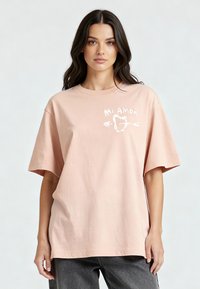 T-shirt en coton rose à coupe décontractée, présentant le texte "Mi Amor" en blanc, accompagné d'un design de cœur et de flèche sur le devant.