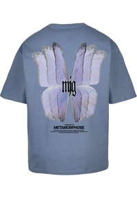 Blue cotton t-shirt featuring a large butterfly graphic in light purple on the back, with bold text reading "mjg" above and "THE STORY OF METAMORPHOSE" below.