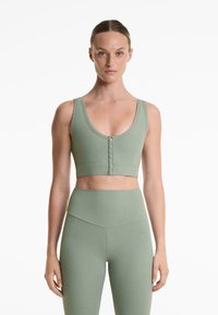 Ribbad, ljusgrön crop top med rundad halsringning och knappstängning. Kombineras med matchande högmidjade ribbade leggings.