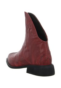 Roter Leder-Stiefelette mit schrägem Design und offenen Seiten. Schwarze, strukturierte Sohle, abgerundete Zehenpartie und dezente Falten im Material.