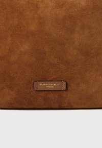 Brun mockaskinnsväska med en slät yta, som har en liten, sydd läderetikett präglad med "GIANNI CHIARINI FIRENZE."