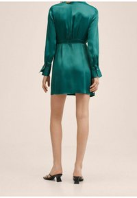 Robe en satin vert avec des manches longues, taille ceinturée et poignets à boutons. Elle présente une silhouette droite, se terminant au-dessus du genou avec une texture lisse.