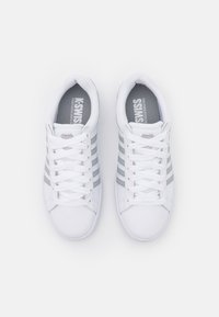 Weiße Sneakers mit grauen Streifen, aus Mesh- und Leder material, runde Zehenkappe, flache Schnürsenkel und einer strukturierten Sohle. K-Swiss-Logo auf der Innensohle.