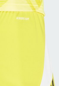 Helle gelbe Sportshorts mit Aeroready-Branding, einem glatten Material und kontrastierenden weißen Akzenten an den Seiten.
