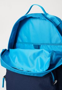 Sac à dos bleu avec un intérieur spacieux et une doublure bleu vif, en tissu, et un dessus zippé pour un accès facile.
