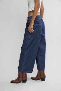 Τζιν παντελόνι με φαρδιά γραμμή, σκούρο ξεβάμμα, ελαστική μέση και κορδόνι. Συνδυασμένο με καφέ μποτάκια με τακούνι, σε πλευρική όψη.